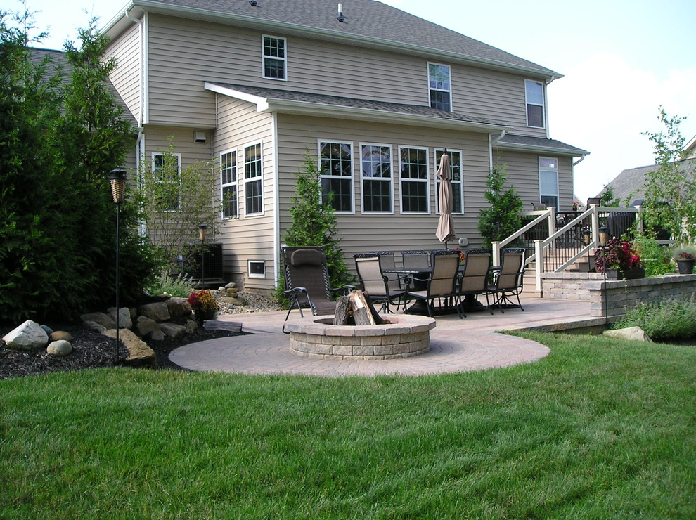 Cette image montre une terrasse arrière traditionnelle de taille moyenne avec un foyer extérieur, des pavés en brique et aucune couverture.
