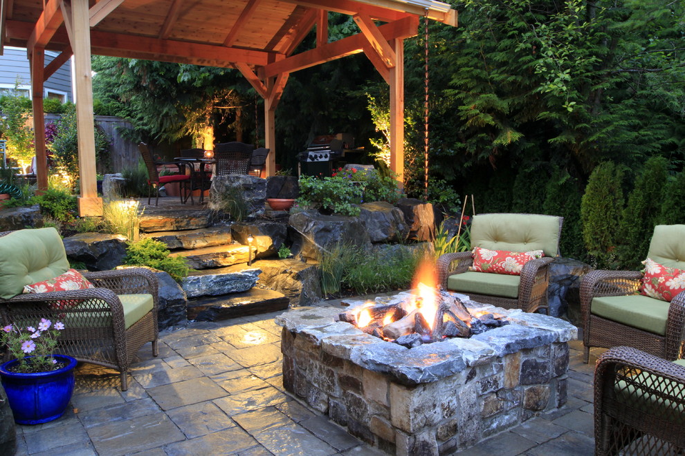 Exemple d'une grande terrasse arrière tendance avec des pavés en pierre naturelle et un gazebo ou pavillon.