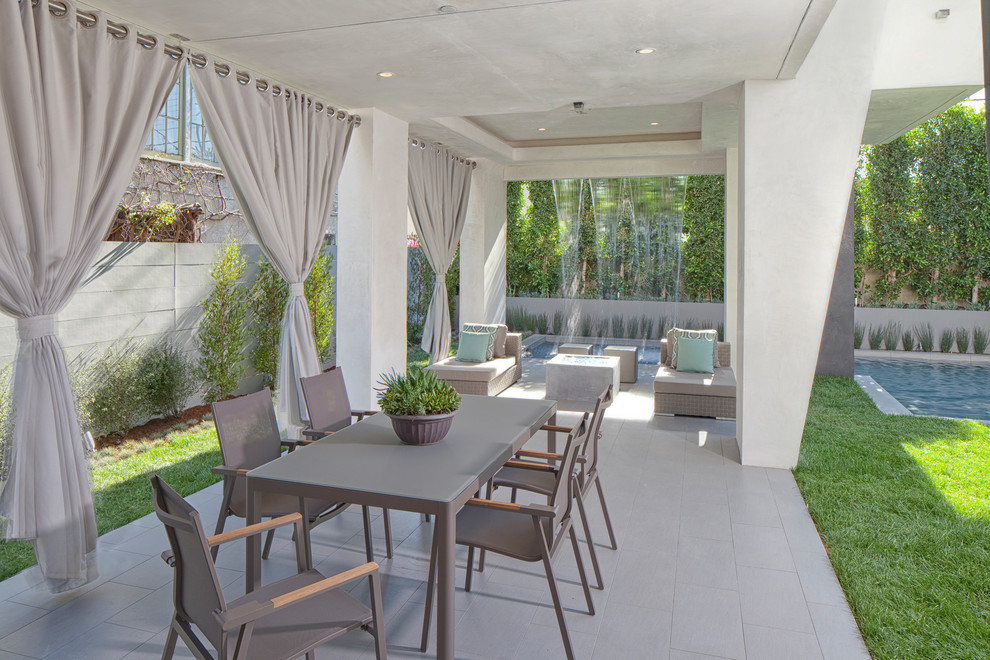 Идея дизайна: большой двор на заднем дворе в современном стиле с покрытием из плитки, навесом и забором
