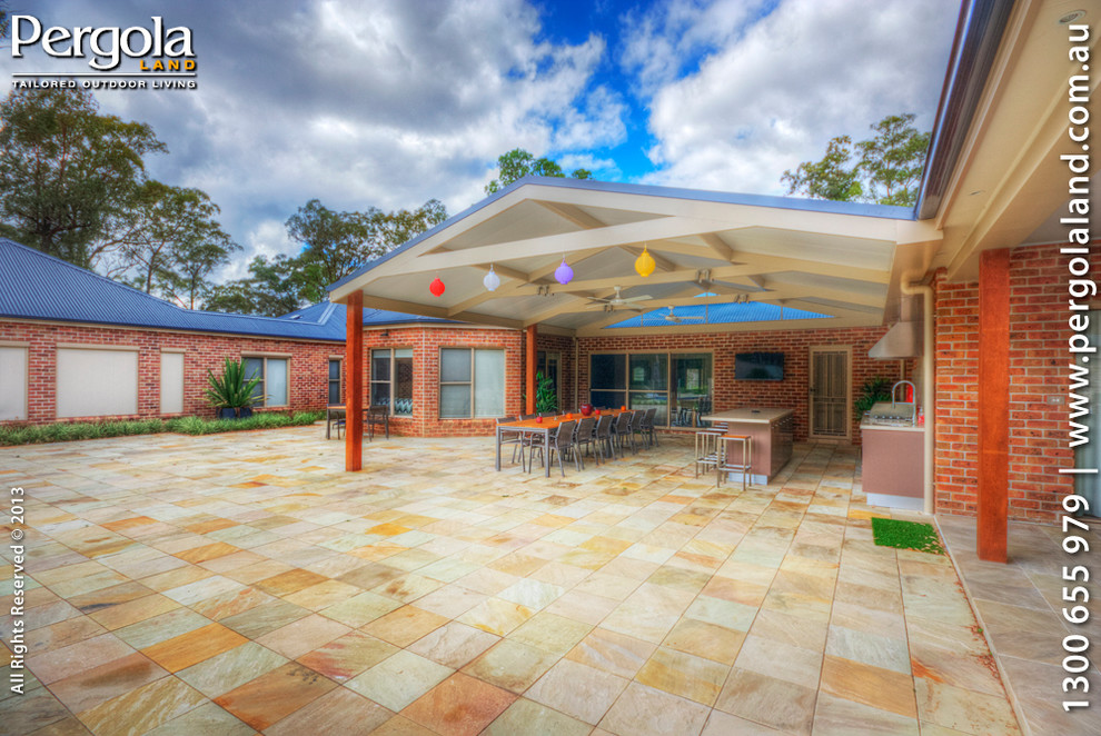 This is an example of a large contemporary courtyard patio in Sydney with natural stone paving and a pergola.