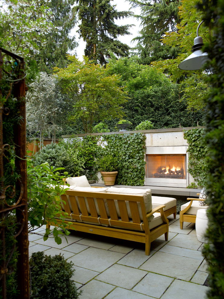 Unbedeckter Moderner Patio hinter dem Haus mit Feuerstelle und Natursteinplatten in Seattle
