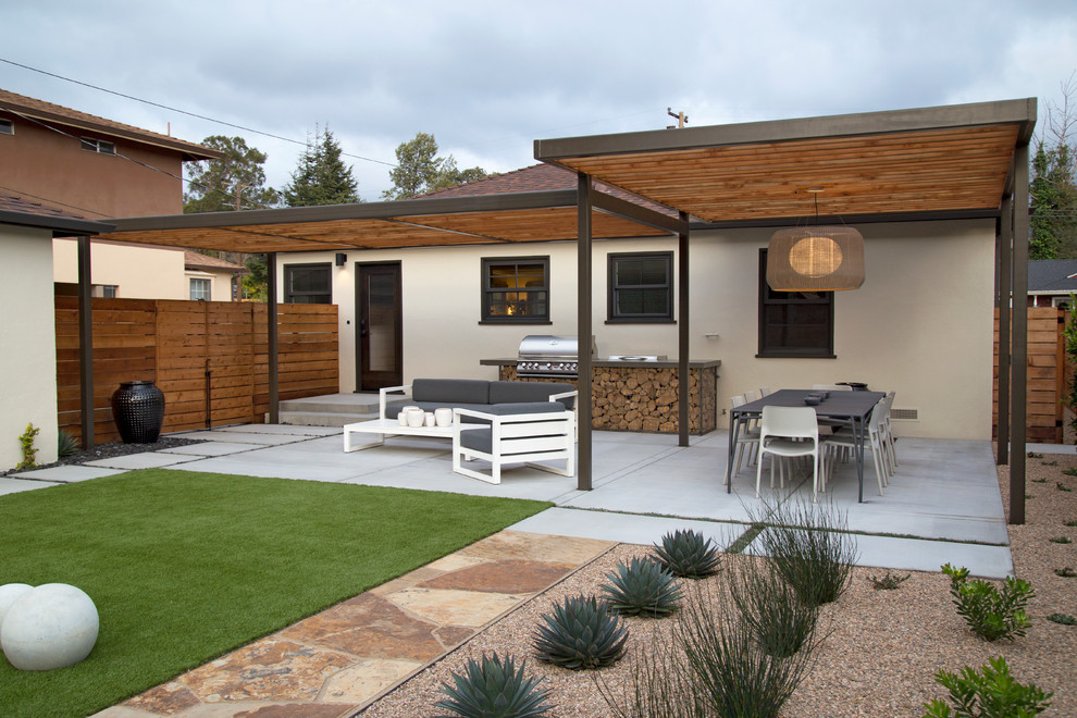 Exemple d'une grande terrasse arrière moderne avec une cuisine d'été, une dalle de béton et une pergola.