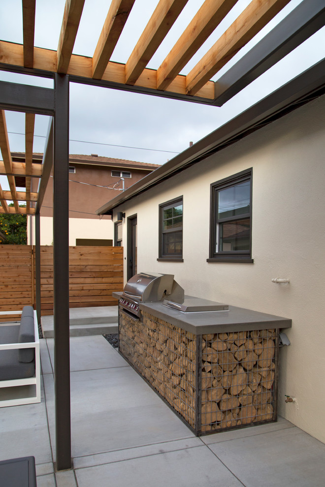 Inspiration pour une grande terrasse arrière minimaliste avec une cuisine d'été, une dalle de béton et une pergola.