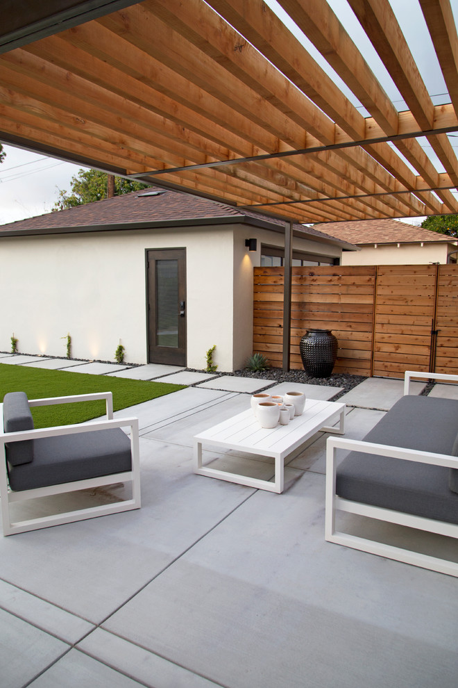 This is an example of a large modern back patio in San Luis Obispo with an outdoor kitchen, concrete slabs and a pergola.