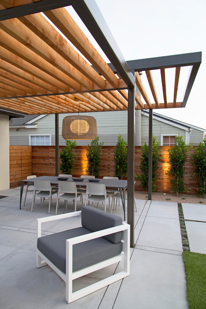 На фото: большая пергола во дворе частного дома на заднем дворе в стиле модернизм с летней кухней и покрытием из бетонных плит с