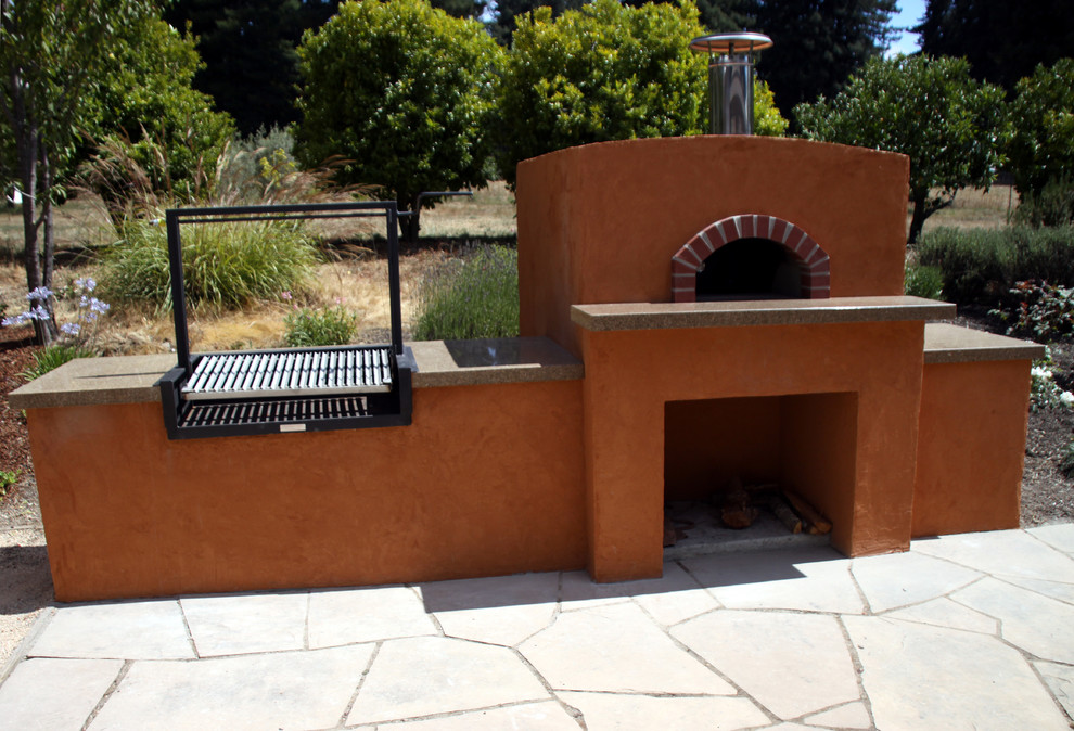 Exemple d'une petite terrasse arrière méditerranéenne avec une cuisine d'été, des pavés en pierre naturelle et aucune couverture.