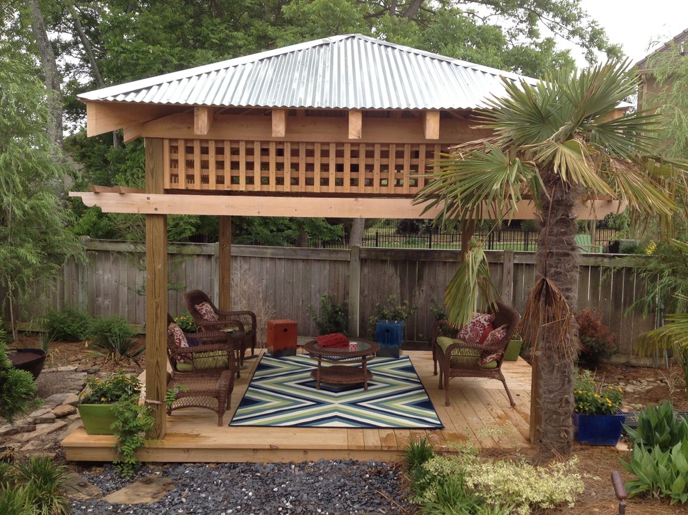 Idee per un patio o portico tropicale di medie dimensioni e dietro casa con pedane e un tetto a sbalzo