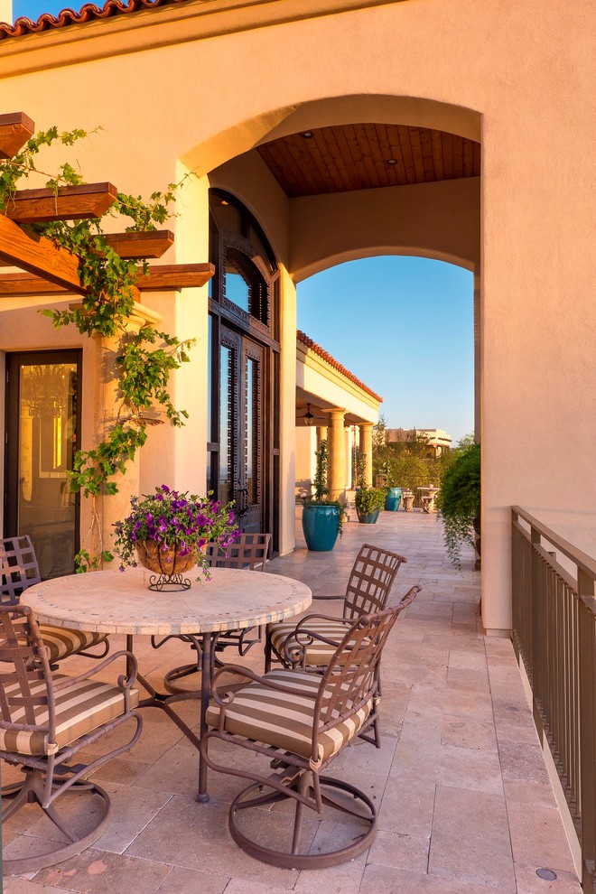 Réalisation d'une terrasse arrière méditerranéenne avec une cuisine d'été, des pavés en pierre naturelle et une extension de toiture.