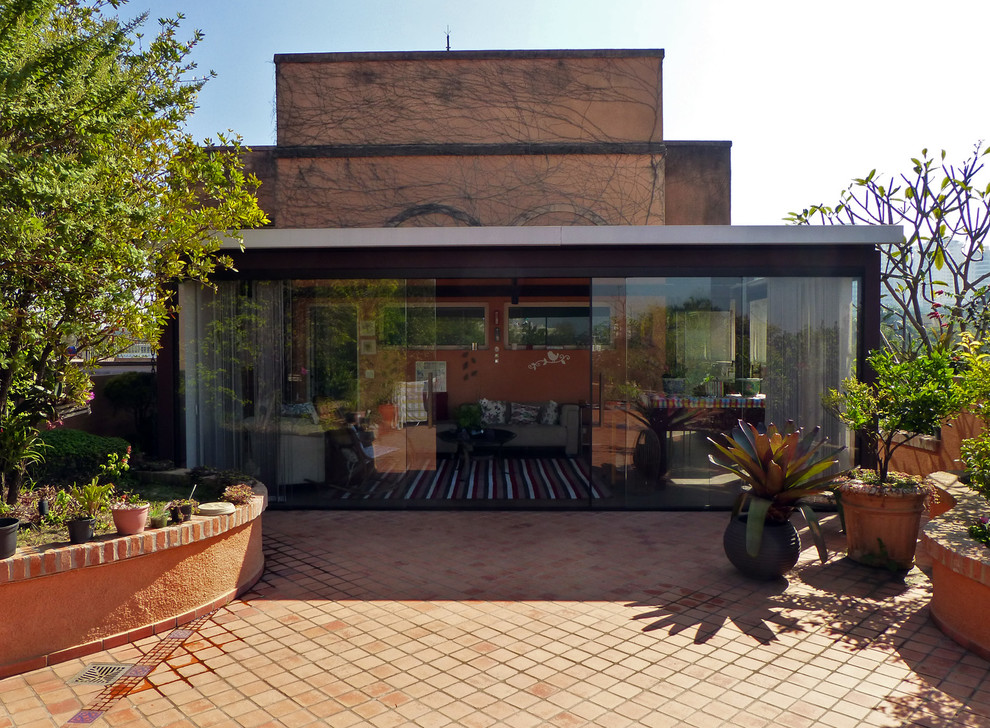 Immagine di un ampio patio o portico stile rurale con piastrelle e un gazebo o capanno