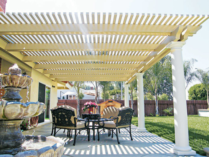 Modelo de patio clásico de tamaño medio en patio trasero con adoquines de hormigón, pérgola y fuente
