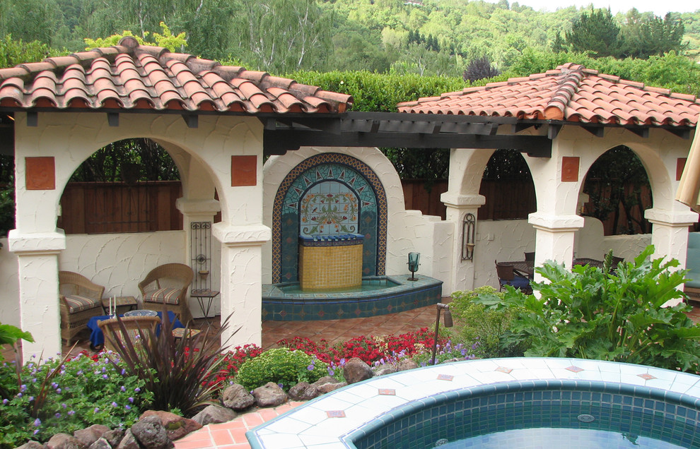 Foto de patio mediterráneo de tamaño medio en patio trasero con fuente, suelo de baldosas y cenador
