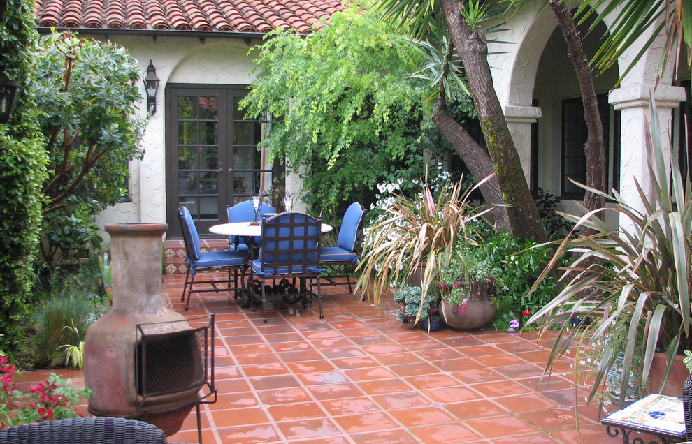 Esempio di un patio o portico mediterraneo di medie dimensioni e in cortile con un focolare, piastrelle e nessuna copertura