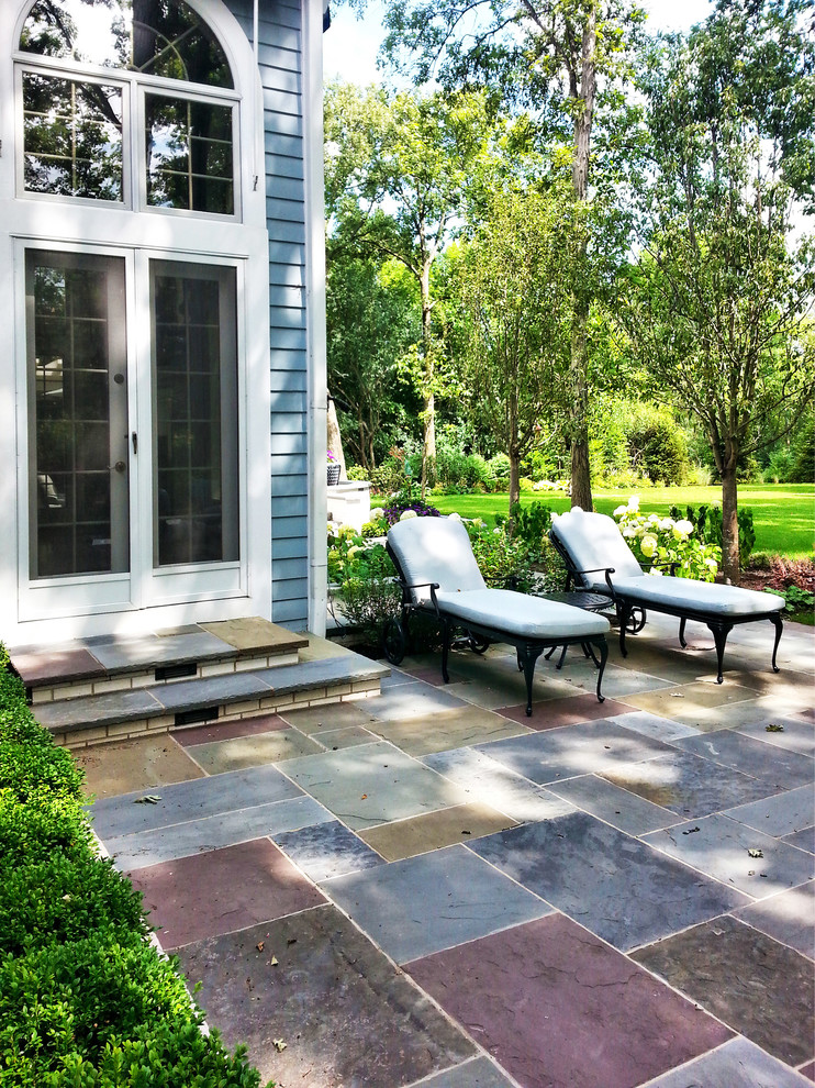 Immagine di un patio o portico classico dietro casa con pavimentazioni in pietra naturale