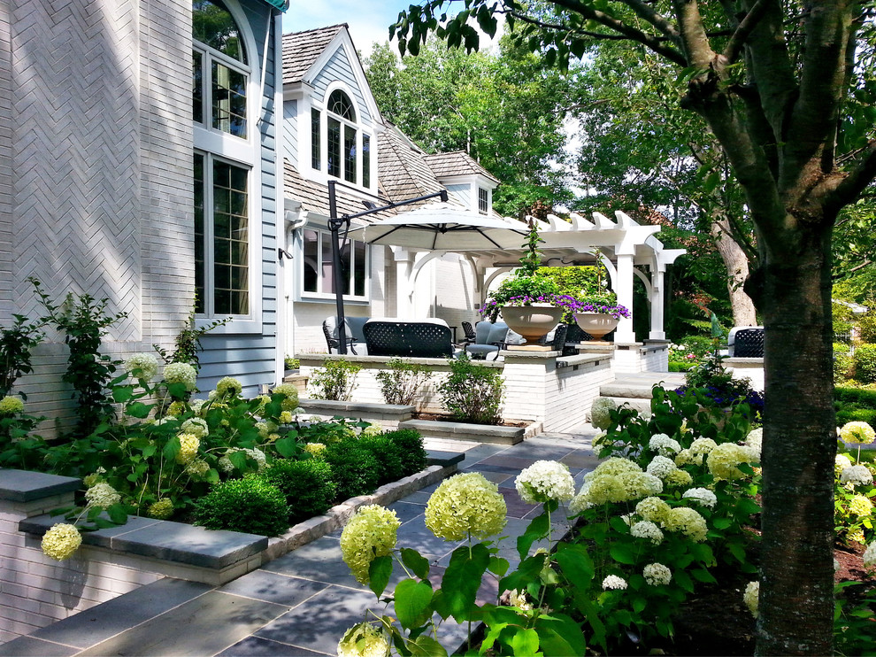 Inspiration for a classic back patio in Chicago with an outdoor kitchen, natural stone paving and a pergola.