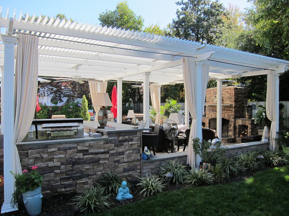 Modelo de patio clásico de tamaño medio en patio trasero con adoquines de piedra natural, pérgola y brasero