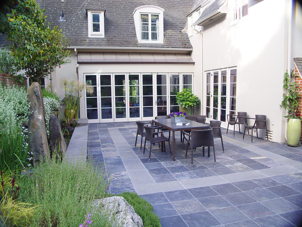 Immagine di un ampio patio o portico contemporaneo dietro casa con piastrelle e una pergola
