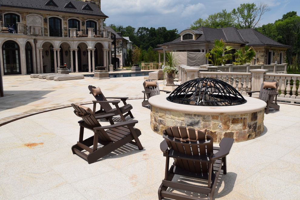 Expansive traditional back patio in New York with a fire feature, natural stone paving and a roof extension.