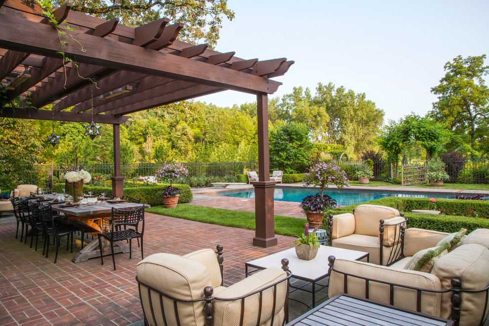 Inspiration for a large traditional back patio in Chicago with brick paving and a pergola.