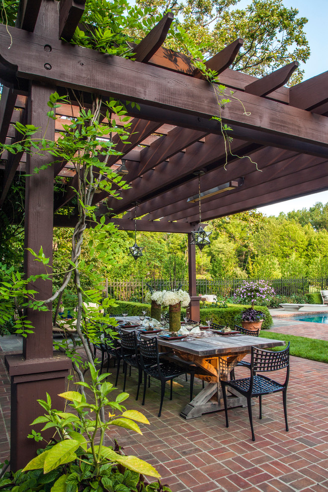 This is an example of a large classic back patio in Chicago with brick paving and a pergola.