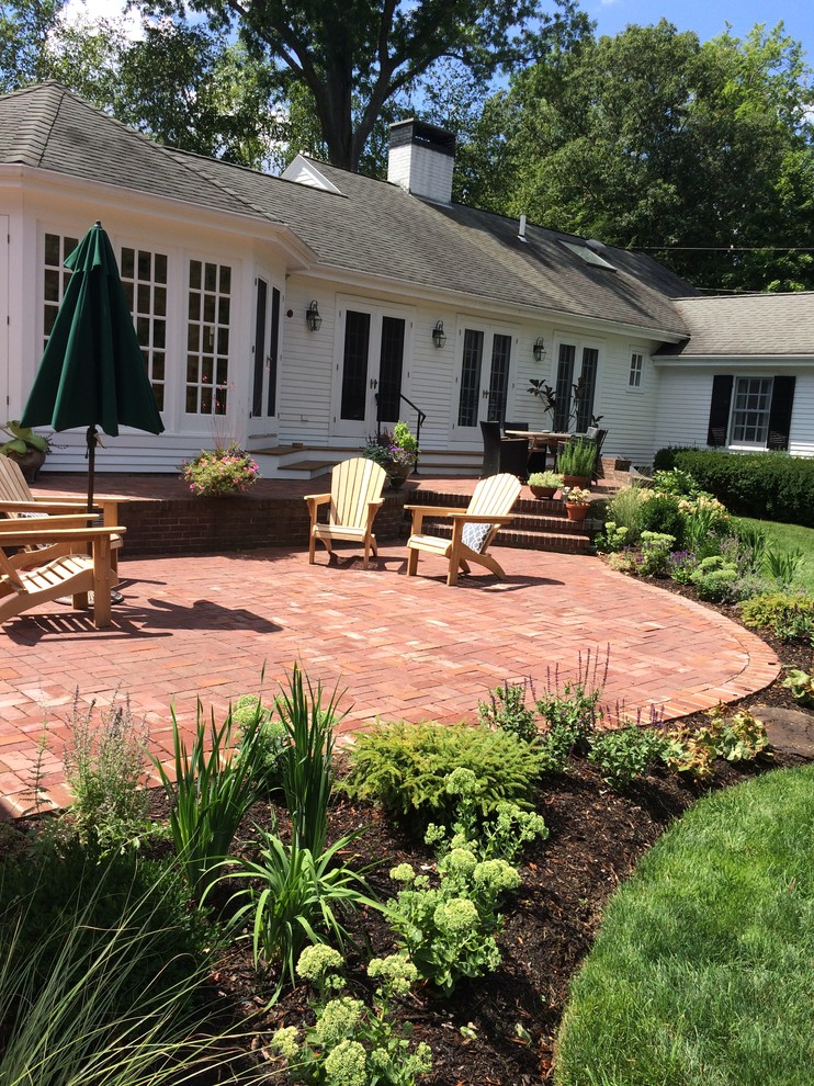 This is an example of a large traditional back patio in Boston with brick paving and no cover.