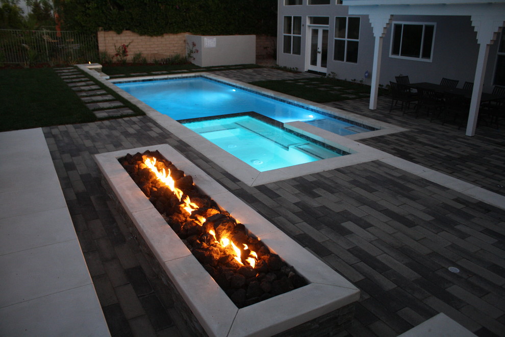 Inspiration for a large contemporary backyard stone patio remodel in Los Angeles with a fire pit and no cover