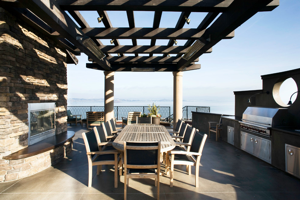 Idée de décoration pour une grande terrasse arrière design avec une cuisine d'été, des pavés en béton et un auvent.
