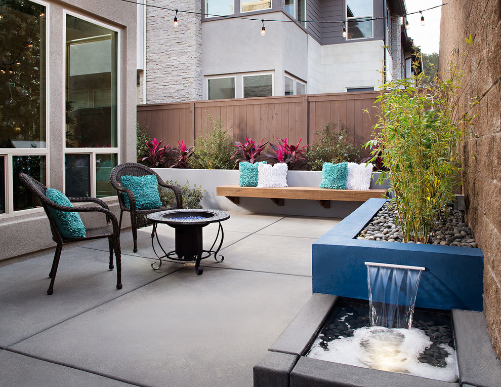 Medium sized contemporary back patio in San Diego with a water feature, concrete slabs and no cover.