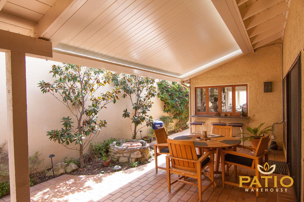 Photo of an urban side patio in Orange County with brick paving and a pergola.