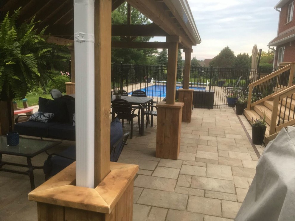 Classic back patio in Toronto with natural stone paving and a pergola.