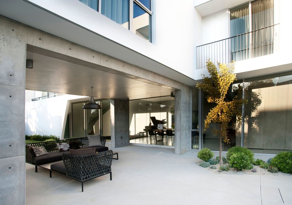 Ispirazione per un patio o portico moderno di medie dimensioni e dietro casa con lastre di cemento e un tetto a sbalzo