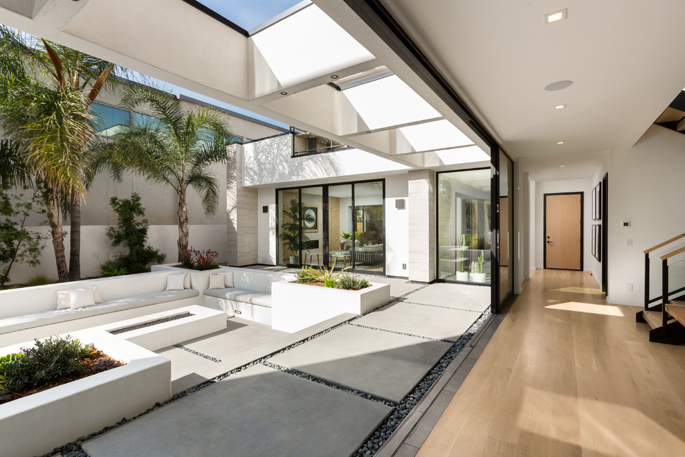 Cette image montre une grande terrasse arrière design avec un foyer extérieur, une dalle de béton et une extension de toiture.