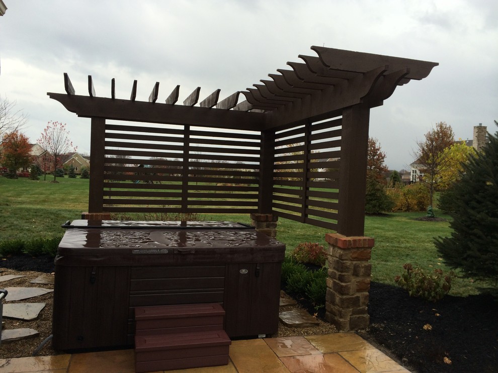 This is an example of a small contemporary back patio in Columbus with natural stone paving and a pergola.