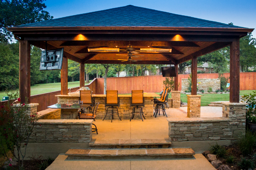 Modelo de patio de estilo americano grande en patio trasero con cocina exterior, losas de hormigón y cenador