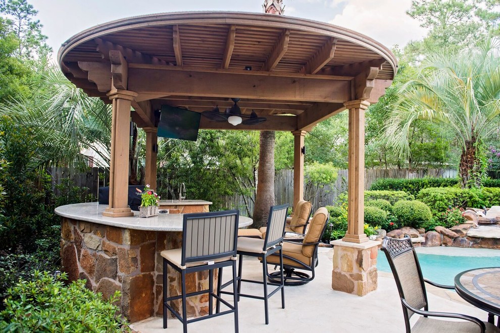 Foto de patio clásico de tamaño medio en patio trasero con cocina exterior, adoquines de piedra natural y pérgola