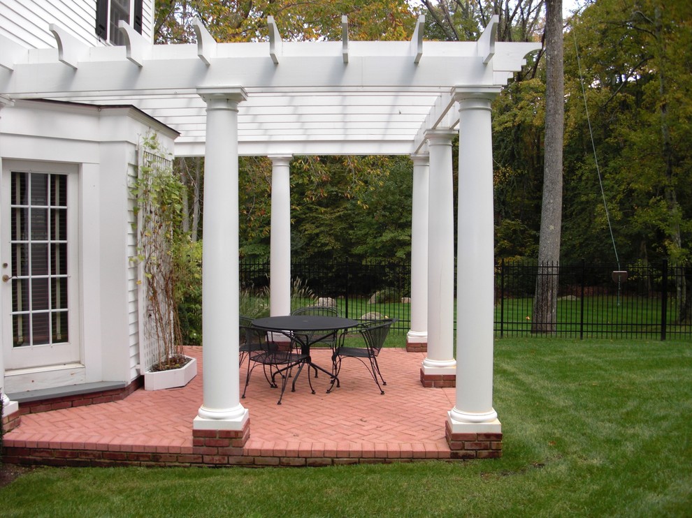 Idee per un grande patio o portico classico dietro casa con pavimentazioni in mattoni e una pergola
