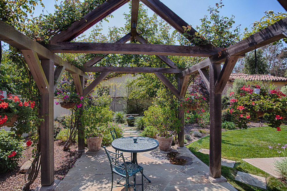Immagine di un piccolo patio o portico dietro casa con pavimentazioni in pietra naturale e una pergola