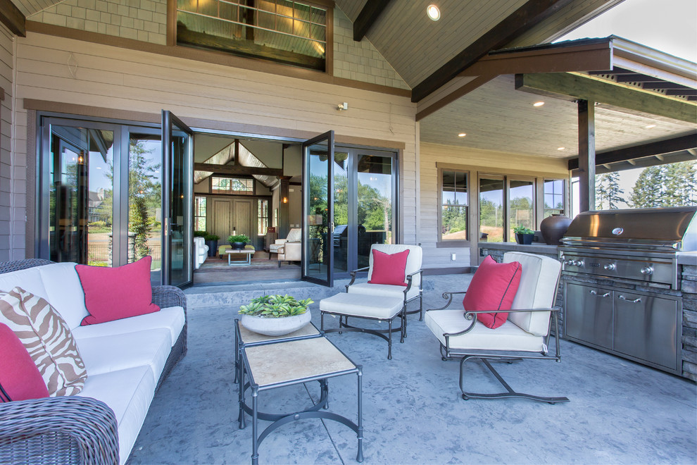 Immagine di un ampio patio o portico stile americano dietro casa con cemento stampato e un tetto a sbalzo