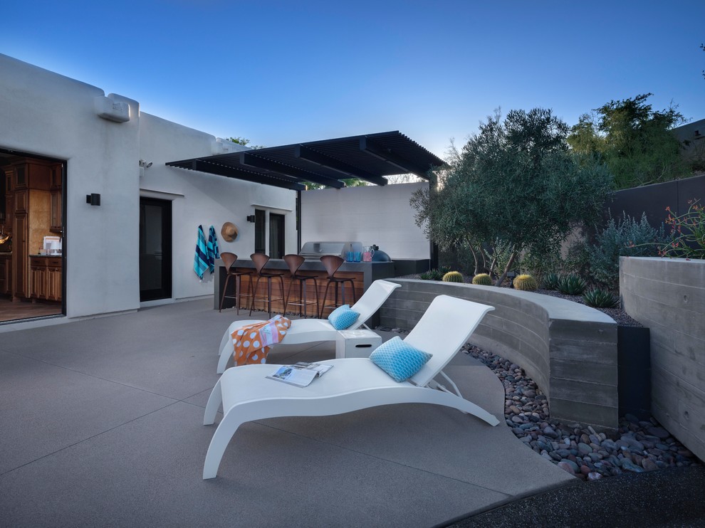Example of a mid-sized trendy backyard concrete paver patio design in Phoenix with a fireplace and a roof extension