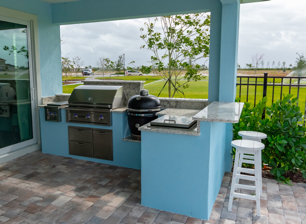 Überdachter Patio hinter dem Haus mit Outdoor-Küche und Pflastersteinen in Miami