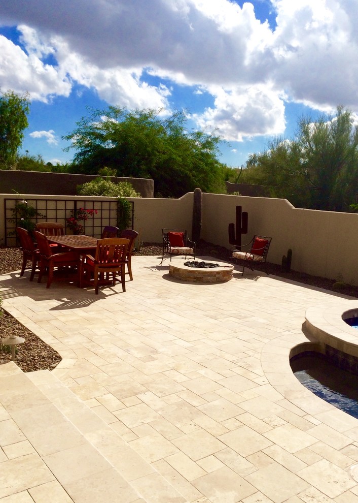 Ejemplo de patio de estilo americano de tamaño medio en patio trasero y anexo de casas con brasero y adoquines de piedra natural