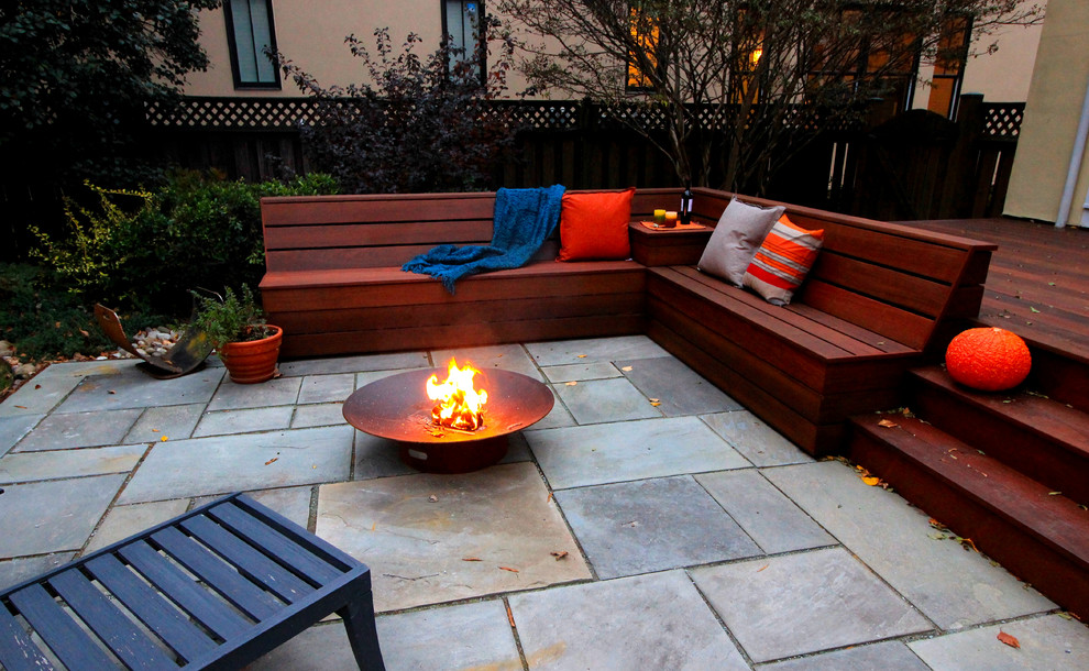 This is an example of a medium sized contemporary back patio in DC Metro with natural stone paving and no cover.