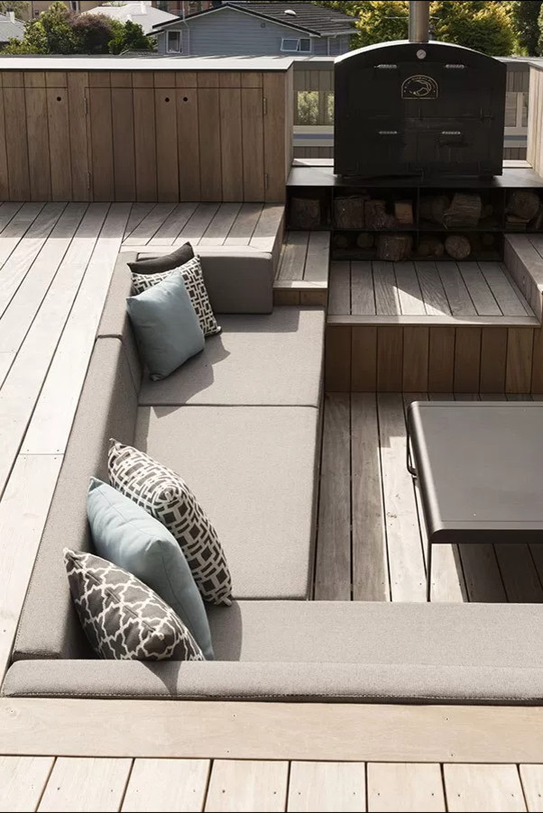 This is an example of a large contemporary courtyard patio in Auckland with a fire feature, decking and no cover.