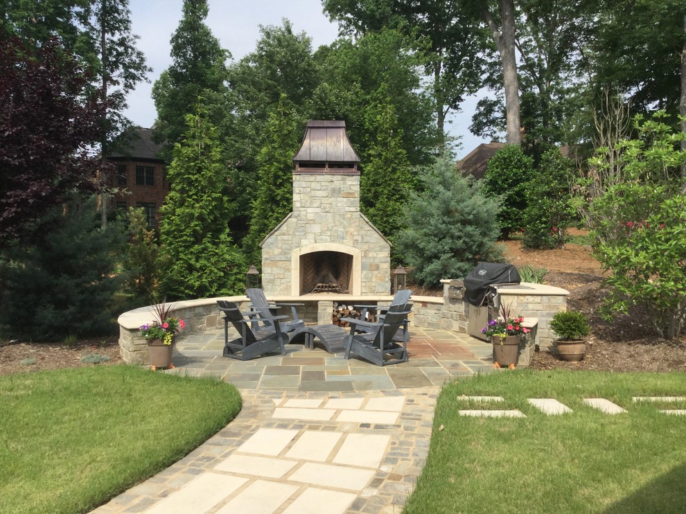 Large contemporary back patio in Atlanta with an outdoor kitchen, natural stone paving and no cover.