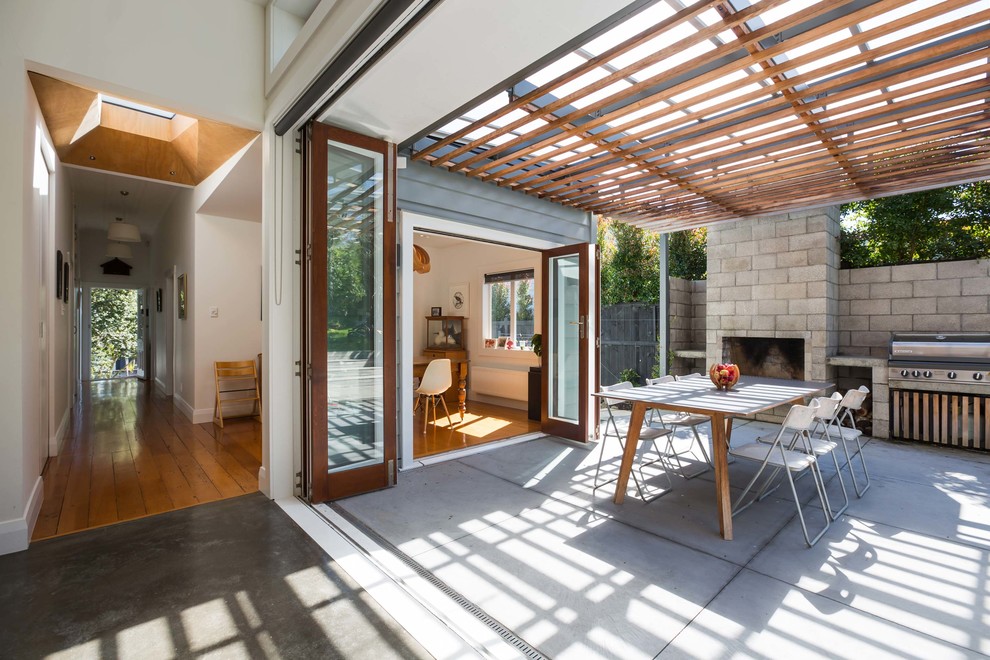 Immagine di un patio o portico minimal dietro casa con lastre di cemento e una pergola