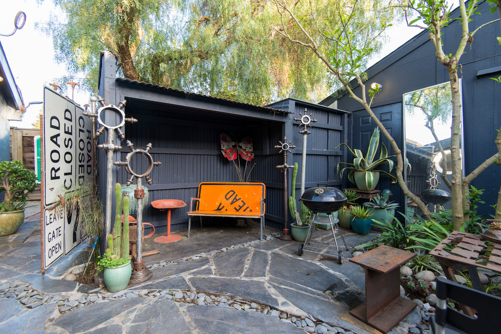 This is an example of a bohemian back patio in San Francisco with natural stone paving and a bbq area.