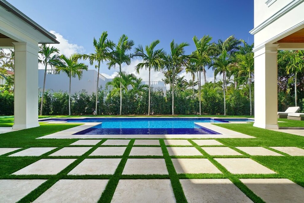 Patio - large tropical backyard concrete paver patio idea in Miami with a roof extension