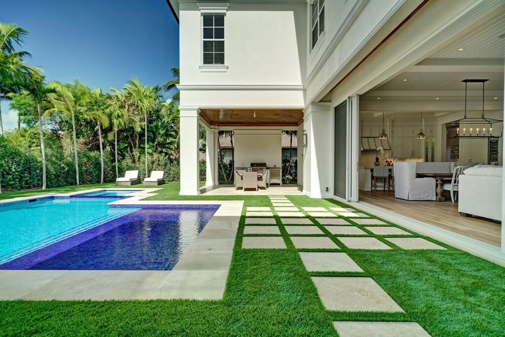 Diseño de patio tropical grande en patio trasero y anexo de casas con adoquines de hormigón