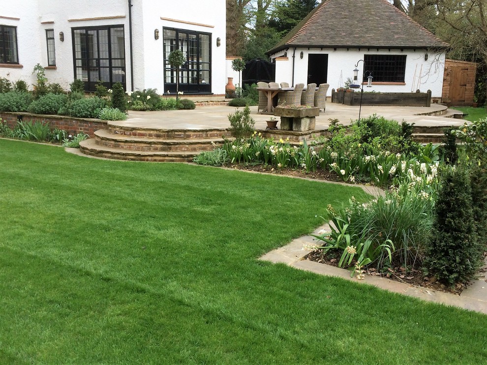 Inspiration for a large classic back patio in London with natural stone paving.