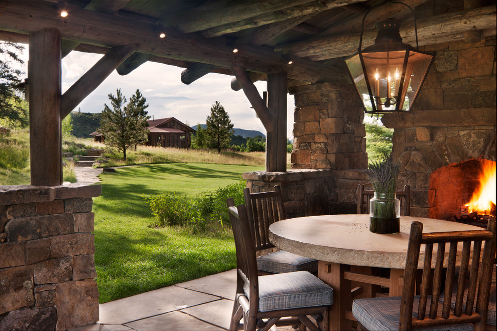 Inspiration pour une terrasse arrière chalet de taille moyenne avec des pavés en pierre naturelle, un gazebo ou pavillon et une cheminée.