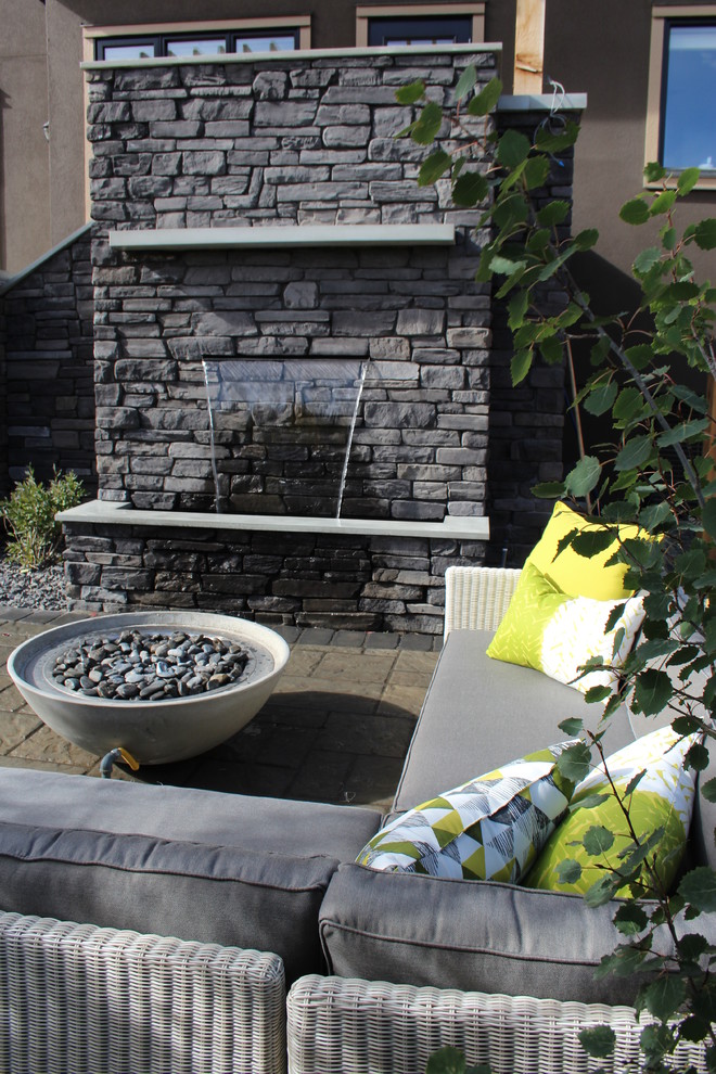 Kleiner, Unbedeckter Moderner Patio hinter dem Haus mit Wasserspiel und Betonboden in Calgary